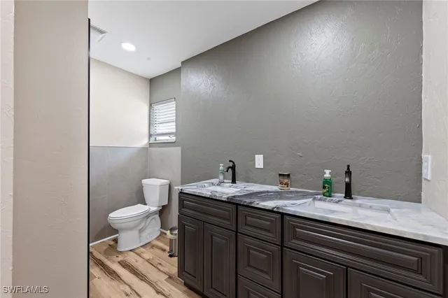 a bathroom with a granite countertop sink a toilet and a mirror