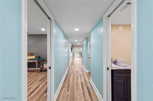 a view of a hallway with wooden floor and a bathroom