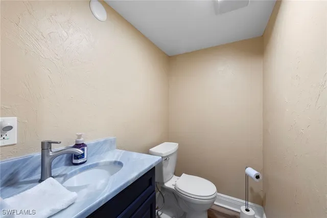 a bathroom with a granite countertop toilet and a sink