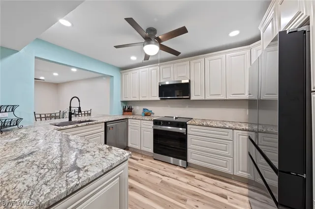 a kitchen with granite countertop a sink appliances and cabinets