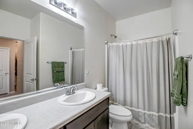 a bathroom with a granite countertop sink a toilet and a mirror