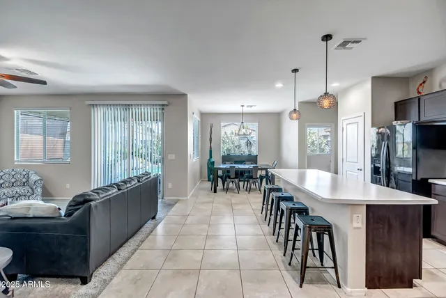 a dining hall with stainless steel appliances granite countertop a refrigerator a sink a dining table and chairs with wooden floor