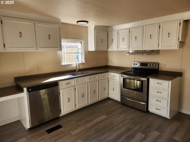 a kitchen with white cabinets white stainless steel appliances and sink