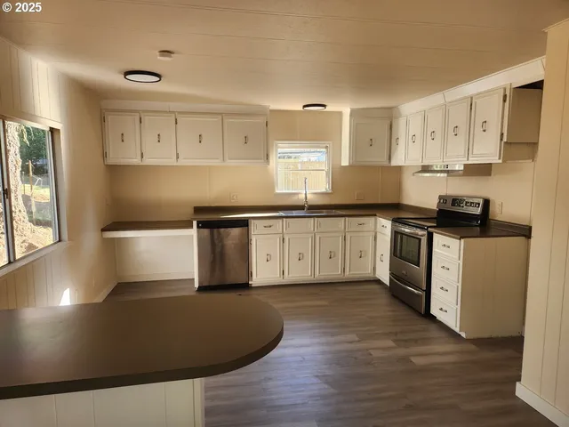 a kitchen with stainless steel appliances granite countertop a stove a sink and white cabinets