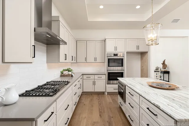 a kitchen with stainless steel appliances a sink dishwasher stove and white cabinets