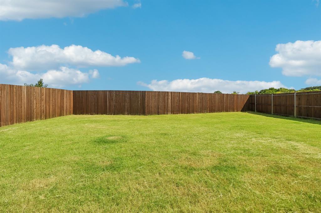 1453 Millstead Rill Road Caddo Mills, TX 75135 - Photo 36 of 40 Expansive grassy yard enclosed by a tall privacy fence, featuring natural wood paneling and corner configuration