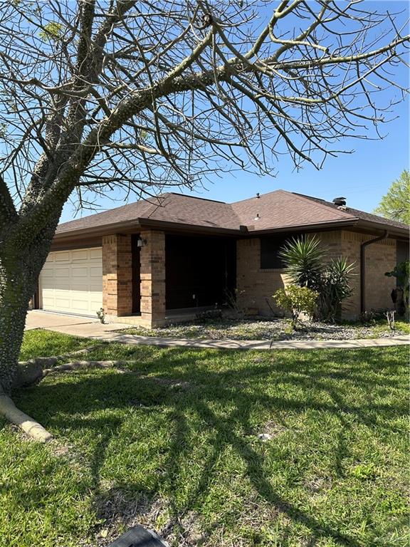 100 West Moore Road, Unit UT21 Pharr, TX 78577 - Photo 1 of 1 View of front of property featuring brick siding, an attached garage, a front lawn, and covered entrance.