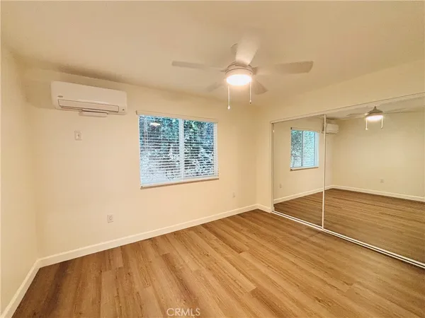 a view of an empty room with window and wooden floor