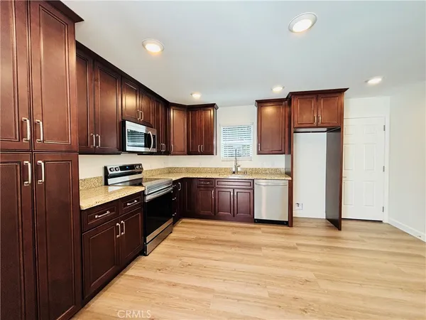 a large kitchen with stainless steel appliances granite countertop a refrigerator and a stove top oven