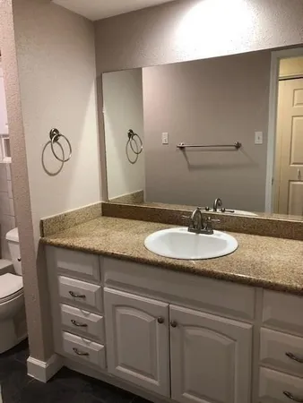 a bathroom with a granite countertop sink and a mirror