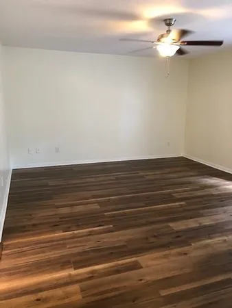 a view of a room with wooden floor and a ceiling fan