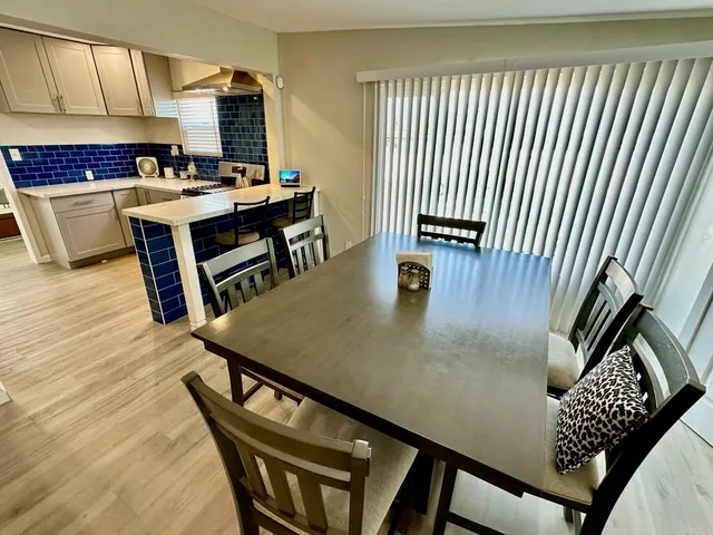a living room with stainless steel appliances furniture a rug and a kitchen view