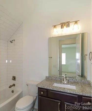 a bathroom with a granite countertop sink vanity mirror and toilet