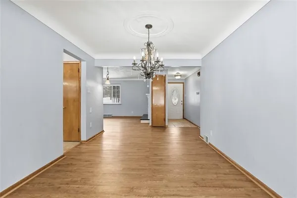 a view of a hallway with wooden floor and a chandelier