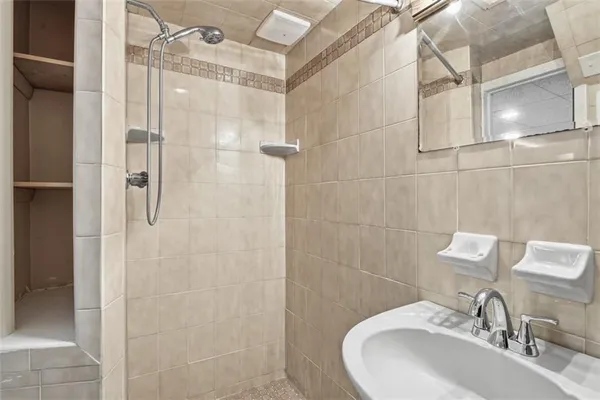a bathroom with a sink shower and a mirror