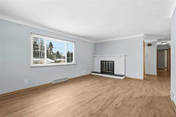 an empty room with windows and fireplace
