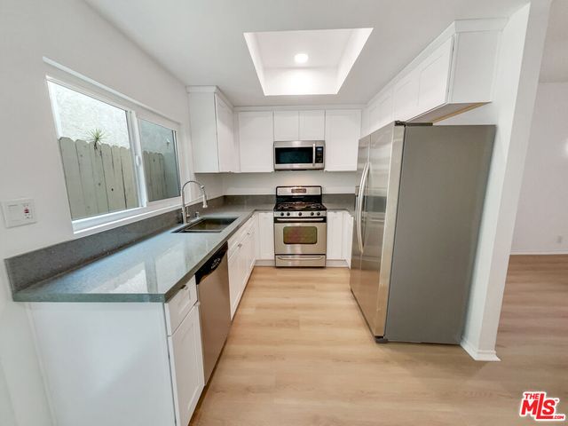 a kitchen with stainless steel appliances granite countertop a refrigerator a stove and a sink