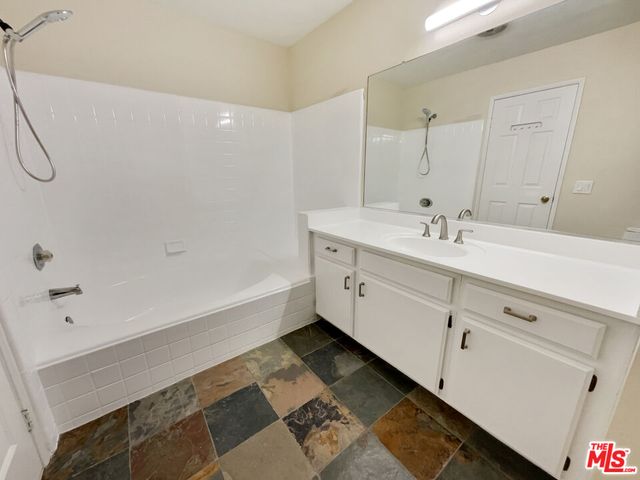 a spacious bathroom with a double vanity sink a mirror and a bathtub