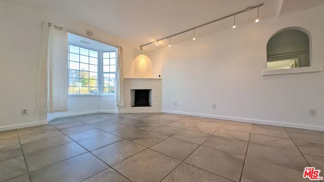 a view of an empty room with a fireplace and a window