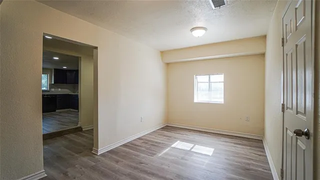 an empty room with wooden floor and a hallway