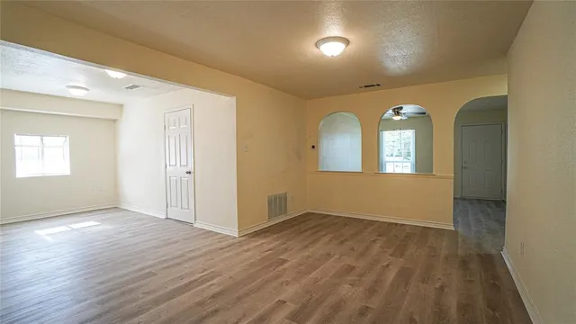 a view of empty room with wooden floor and fan