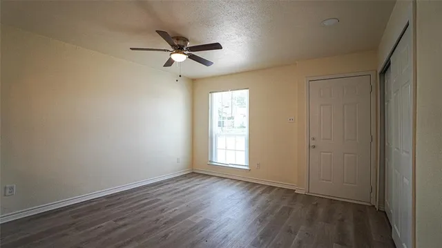 a view of empty room with wooden floor and fan