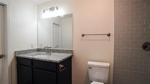 a bathroom with a granite countertop sink toilet and mirror