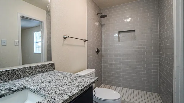 a bathroom with a granite countertop toilet sink and shower