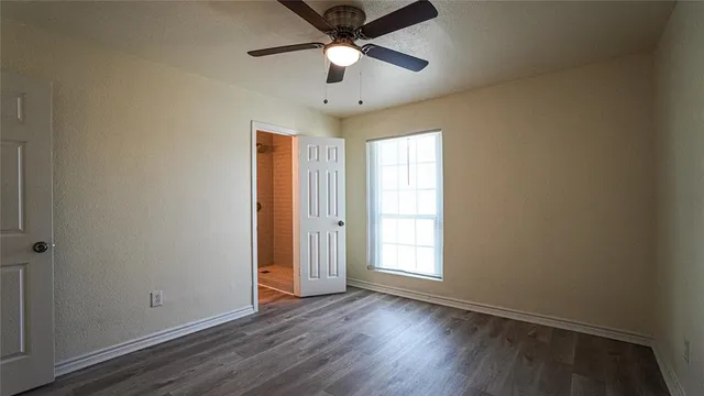 a view of empty room with wooden floor and fan