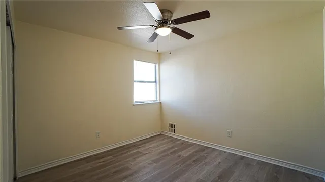 an empty room with a window and a fan