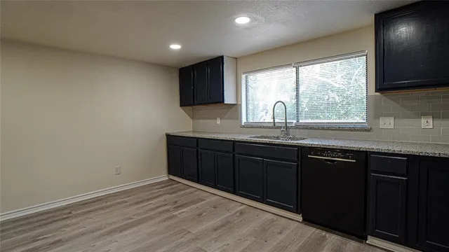a kitchen with granite countertop a stove a sink and a window