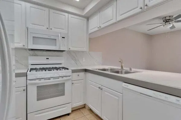 a kitchen with granite countertop white cabinets and white appliances