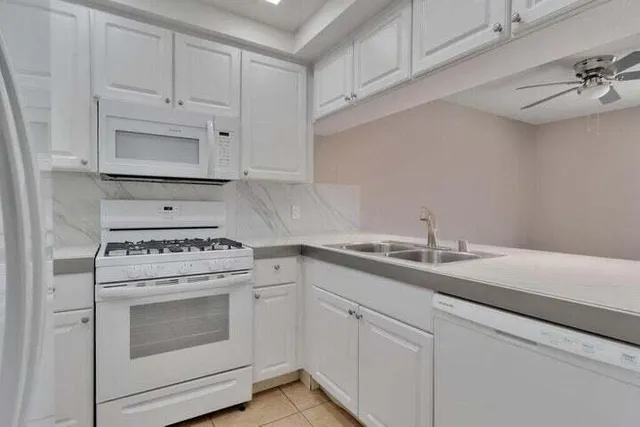a kitchen with granite countertop white cabinets and white appliances
