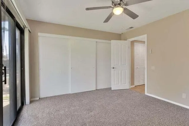 a view of an empty room and chandelier fan