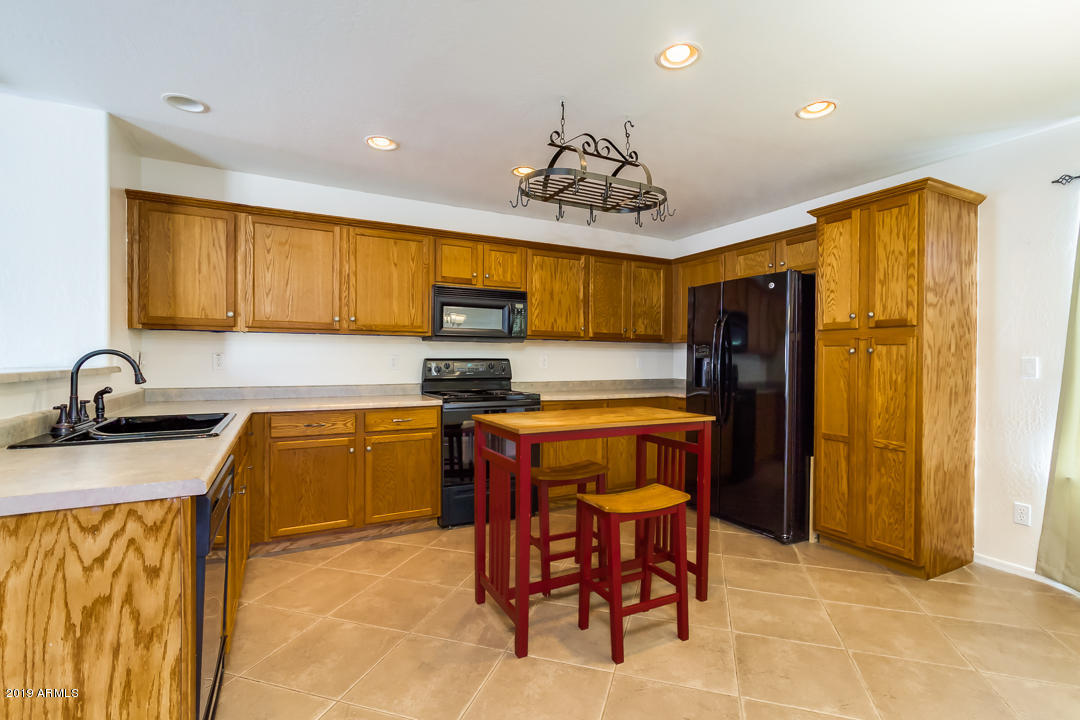 1986 West Tanner Ranch Road Queen Creek, AZ 85144 - Photo 13 of 32 a kitchen with stainless steel appliances granite countertop a sink a stove cabinets dining table and chairs