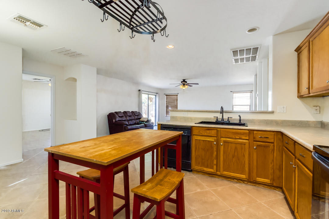 1986 West Tanner Ranch Road Queen Creek, AZ 85144 - Photo 16 of 32 a kitchen with stainless steel appliances granite countertop a table chairs sink and cabinets