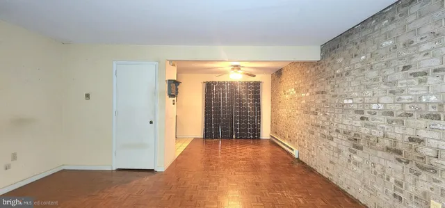 a view of a hallway with wooden floor and a bathroom