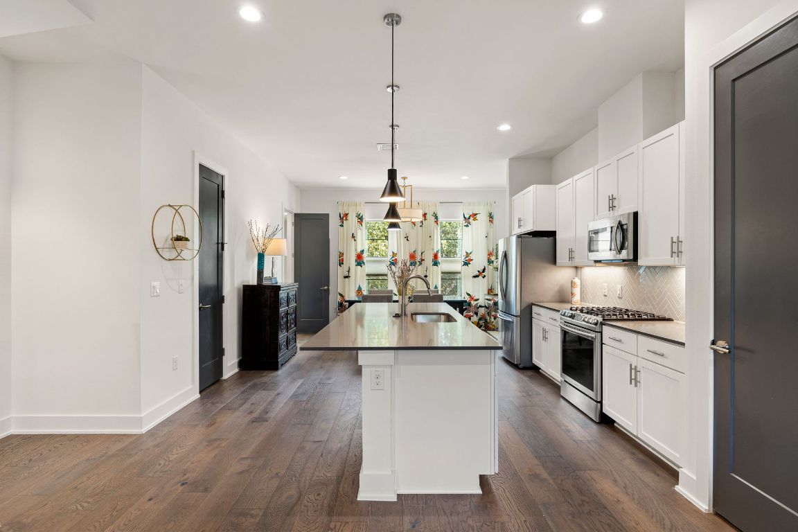 3700 Clawson Road, Unit 503 Austin, TX 78704 - Photo 11 of 39 a large kitchen with stainless steel appliances kitchen island granite countertop a stove a refrigerator a oven and white cabinets with wooden floor