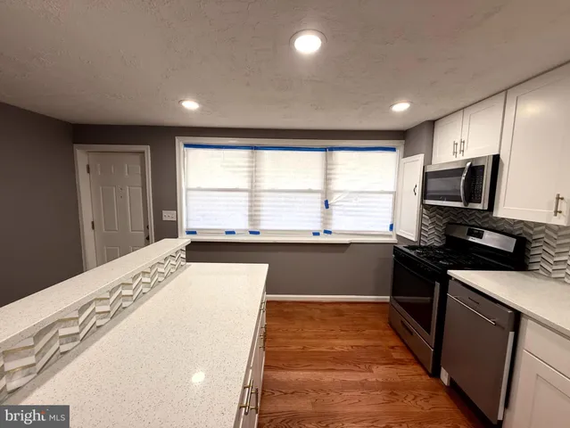 a kitchen with stainless steel appliances a microwave a sink and white cabinets