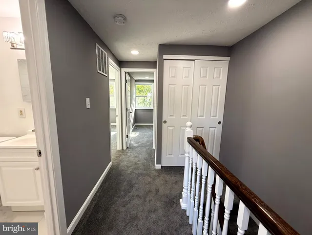 a view of a hallway with wooden floor and a bathroom