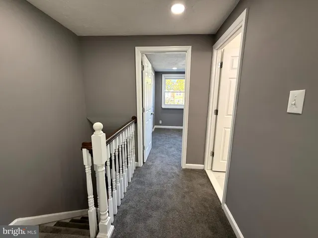 a view of a hallway with wooden floor and a bathroom