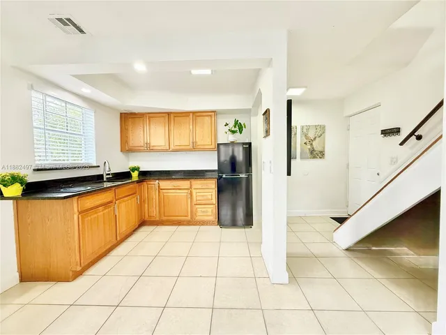 a large kitchen with stainless steel appliances granite countertop a refrigerator and a sink