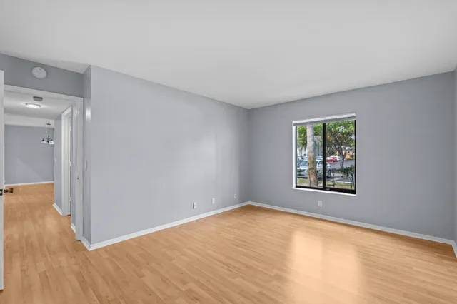 a view of an empty room with wooden floor and a window