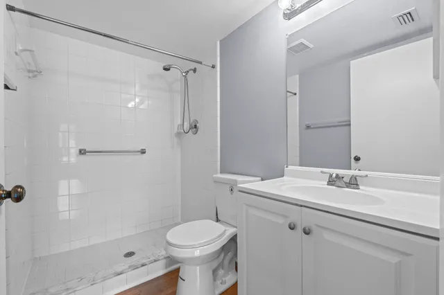 a bathroom with a granite countertop sink a toilet and shower