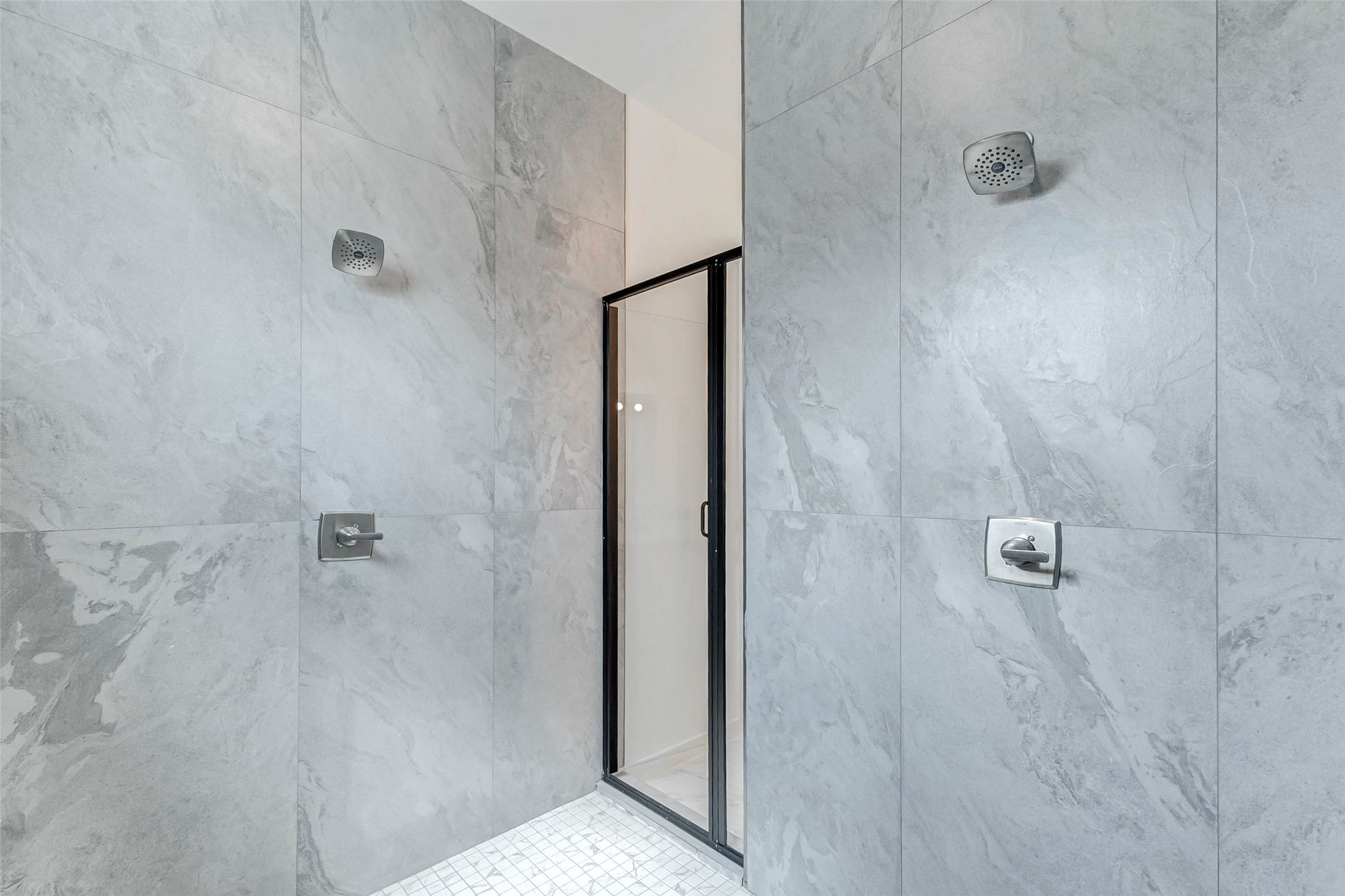 6017 Beall Street Houston, TX 77091 - Photo 18 of 33 Step into your own private spa! This oversized walk-in shower is wrapped in modern slate-style tile with dual shower heads and sleek black trim for a luxurious, high-end finish.