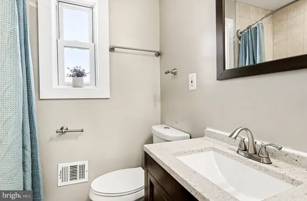 a bathroom with a granite countertop toilet sink and mirror