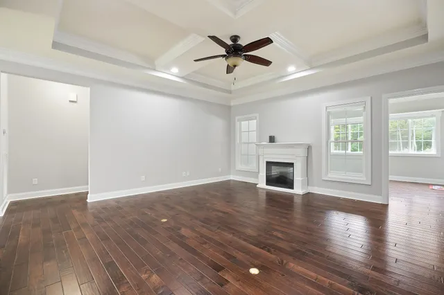 a view of an empty room with wooden floor fireplace and a window