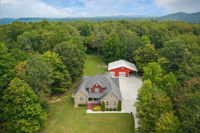 an aerial view of a house with pool lake and mountain view