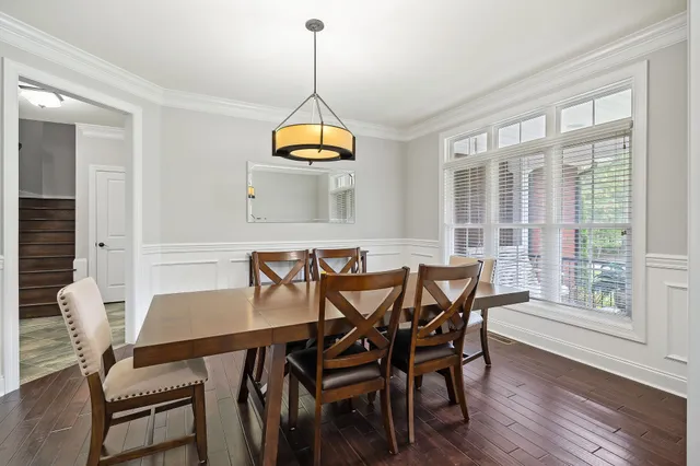 a view of a livingroom and a dining room with wooden floor chandelier
