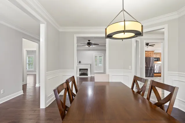 an empty room with wooden floor a ceiling fan a fireplace and windows